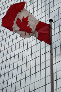 Canada flag flying in front of an office skyscraper